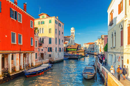 Venice, Italy, September 13, 2019: people tourists are walking down fondamenta embankment promenade of narrow water canal with moored boats and old buildings in historical city center, Veneto regionのeditorial素材