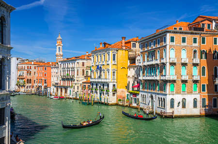 Venice, Italy, September 13, 2019: gondolier on gondola traditional boat sailing on water of Grand Canal waterway with Venetian architecture typical colorful buildings and bell tower backgroundのeditorial素材