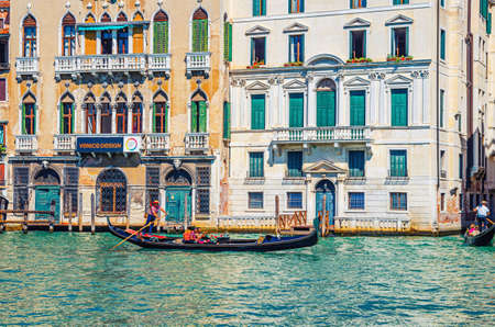 Venice, Italy, September 13, 2019: gondolier and tourists on gondola traditional boat sailing on water of Grand Canal waterway with Venetian architecture typical colorful buildings backgroundのeditorial素材