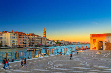 Venice, Italy, September 13, 2019: Fondamenta Salute embankment promenade near pier of Grand Canal waterway at sunset, Campanile bell tower and row of baroque style buildings in San Marco sestiereのeditorial素材