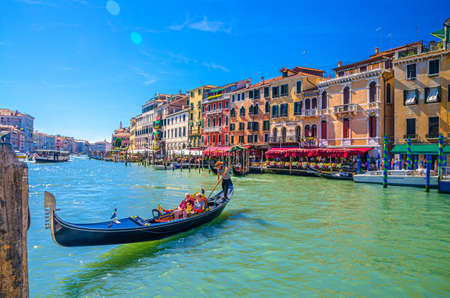 Venice, Italy, September 13, 2019: gondolier and tourists on gondola traditional boat sailing on water of Grand Canal waterway with Venetian architecture typical colorful buildings backgroundのeditorial素材