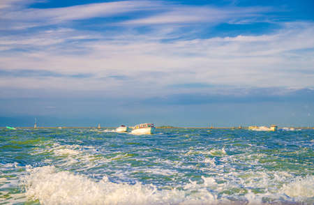 Yacht boats racing sailing on water of Venetian lagoon between wooden poles near Venice city coast, island at horizon, Veneto region, Northern Italyの写真素材