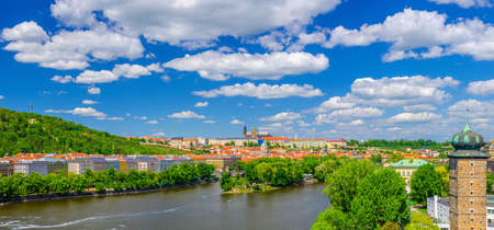 Panorama of Prague city historical center with Prague Castle, St. Vitus Cathedral, Hradcany district, green hills and Vltava river, blue sky. Aerial panoramic view of Prague city, Czech Republicの写真素材