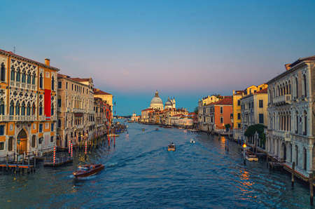 Venice cityscape with Grand Canal waterway. Buildings with evening lights along Grand Canal. Santa Maria della Salute Roman Catholic church on Punta della Dogana at twilight. Veneto Region, Italy.の写真素材