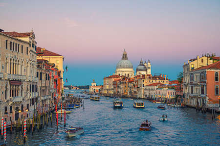 Venice cityscape with Grand Canal waterway. Buildings with evening lights along Grand Canal. Santa Maria della Salute Roman Catholic church on Punta della Dogana at twilight. Veneto Region, Italy.の写真素材