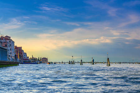 Yacht boats racing sailing on water of Venetian lagoon between wooden poles near Venice city coastline, island at horizon, Veneto region, Northern Italyの写真素材