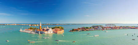 Aerial panoramic view of Venetian Lagoon with San Giorgio Maggiore island, Lido island and Giudecca island, sailing boats in Giudecca Canal, blue sky, Venice city, Italy. Panoram of venetian lagoonの写真素材