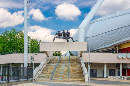 Minsk, Belarus, July 26, 2020: Dinamo National Stadium entrance with sculpture running men runners monument and staircase in historical center, blue sky white clouds in sunny summer dayのeditorial素材