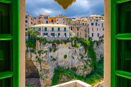 Tropea, Italy - May 9, 2018: Buildings on stone rock cliff in Tropea town historical center, view through window of Monastery Sanctuary church Santa Maria dell Isola, Vibo Valentia, Calabriaのeditorial素材