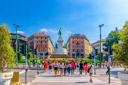 Milan, Italy, September 9, 2018: people crossing road street near Monument Giuseppe Garibaldi statue on Largo Cairoli square and old traditional buildings in summer day, blue sky background, Lombardyのeditorial素材