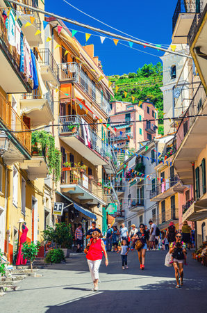 Manarola, Italy, September 12, 2018: colorful buildings houses with flags rows, balconies, shutter windows on narrow street of typical traditional fishing village National park Cinque Terre, Liguriaのeditorial素材