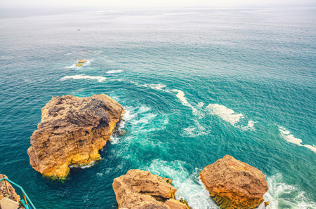 Top aerial view of waves crashing cliffs and small rock islands in azure turquoise water of Atlantic...
