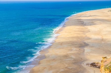 Top aerial panoramic view of sandy beach, waves of azure blue water of Atlantic Ocean and endless horizon near Nazare town, North beach Praia do Norte, Leiria District, Oeste region, Portugalの写真素材