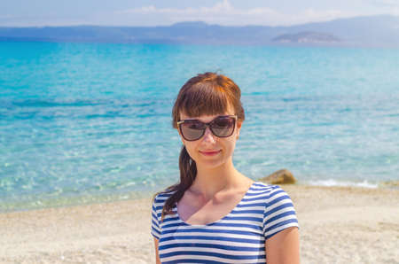 Close-up portrait of young beautiful girl with striped t-shirt and sunglasses looking at camera and...
