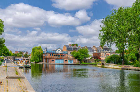 Somme river water canal with rowing club old building and motor ship tourist boat moored docked on embankment in Amiens historical centre, Somme department, Hauts-de-France Region, Northern Franceの写真素材
