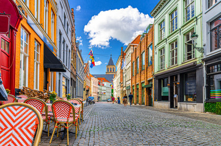 Brugge city historical centre, street restaurant with tables and chairs, paving stone road, colorful buildings in Bruges old town quarter medieval district, West Flanders province, Belgiumの写真素材
