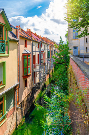 Colorful small buildings with balconies and bay windows near narrow water canal in Amiens town...