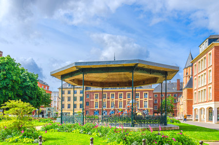 Bandstand band shell music pavilion stage in Square Jules Bocquet, lawn with green grass and flowers and Maison du Sagittaire Sagittarius house in Amiens city centre, Hauts-de-France Region, Franceの写真素材