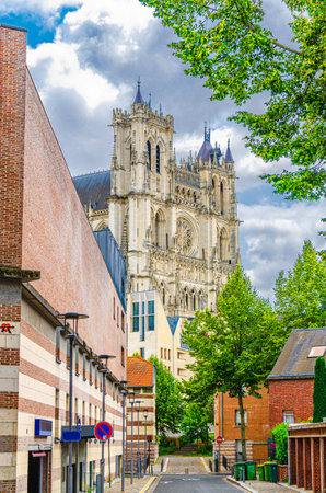 Cathedral Basilica of Our Lady of Amiens Roman Catholic church Notre-Dame behind buildings on street in historical city centre, vertical view, Somme department, Hauts-de-France Region, Franceの写真素材