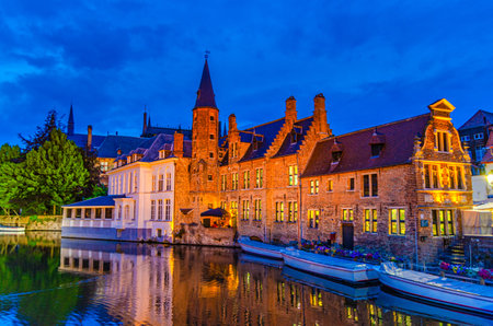 De groote Hollander Huidevettershuis and restaurant in Brugge old town, Bruges historical city centre, Rosary Quay embankment with motor boats, Dijver water canal of Reie river, evening view, Belgiumの写真素材