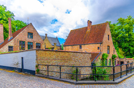 Begijnhof Beguinage old brick buildings with chimney and tiled roofs near water canal in Brugge city historical centre, Bruges old town district, West Flanders province, Flemish Region, Belgiumの写真素材