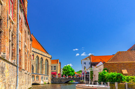 Bakkersrei water canal, Mary's Bridge and medieval Museum Sint-Janshospitaal building with green plants and trees in Brugge old town quarter, Bruges city historical centre, Flemish Region, Belgiumの写真素材