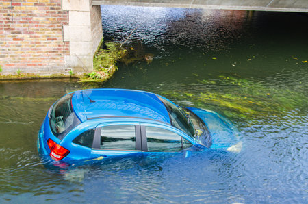 Blue vehicle in water canal. Extreme accident car in river pound lake, traffic incidentの写真素材