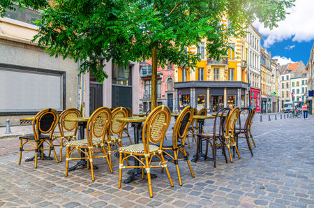Street restaurant with wooden tables and chairs on cozy street, road with paving stone and tree, old colorful buildings, Lille city historical center, French Flanders, Hauts-de-France Region, Franceの写真素材
