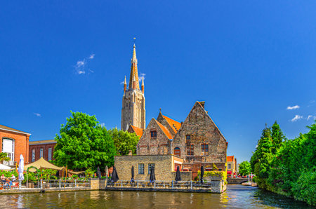 Bakkersrei water canal, Roman Catholic Church of Our Lady Gothic style and Sint-Janshospitaal building on embankment in Brugge old town, Bruges city historical centre, West Flanders province, Belgiumの写真素材