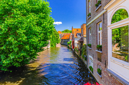 Bakkersrei water canal of Reie river and medieval houses buildings walls with green trees on riverside in Brugge old town quarter district, Bruges city historical centre, Flemish Region, Belgiumの写真素材
