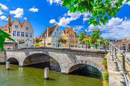 Bruges cityscape, Carmersbrug across Langerei water canal, arch bridge and medieval houses on promenade embankment in sunny day, Brugge old town, Bruges city historic centre, Flemish Region, Belgiumの写真素材