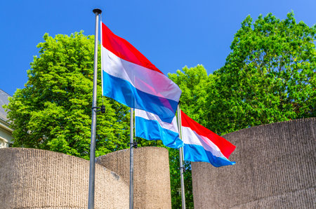 Luxembourg flags in front of National Monument of Solidarity at Cannon Hill Kanounenhiwwel, green trees and blue sky in Luxembourg city historical centerの写真素材