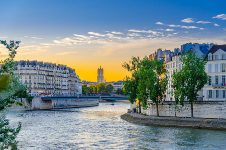 Paris city historic center with typical Parisian buildings on embankment of Seine river, Pont Saint-Louis pedestrian bridge between Ãle de la Cite and Ãle Saint-Louis islands on sunset, Franceの写真素材