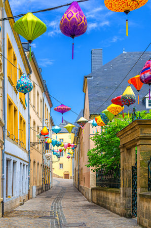 Narrow pedestrian empty street with colorful paper lanterns between buildings in old town Ville Haute quarter in Luxembourg City historical center with blue sky background in summer dayの写真素材