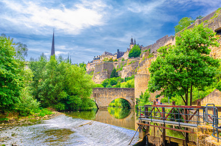 Alzette Valley in Grund district Lower town of Luxembourg City center with Wenzel wall Pont du Stierchen bridge across Alzette river with small waterfall, Bock Promontory Casemates fortification wallの写真素材