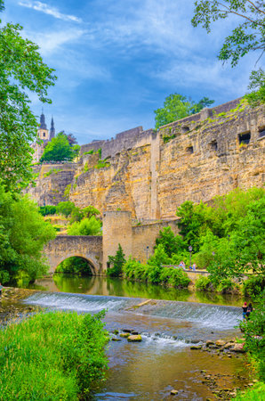 Alzette Valley in Grund district Lower town of Luxembourg City center with Wenzel wall Pont du Stierchen bridge across Alzette river with small waterfall, Bock Promontory Casemates fortification wallの写真素材