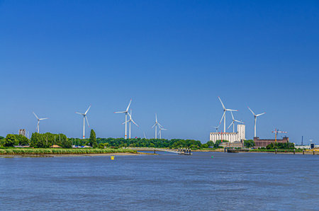 Landscape of Scheldt river and Linkeroever Left bank of Antwerp with Windmill farm wind power plant...