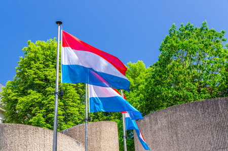 Luxembourg flags in front of National Monument of Solidarity at Cannon Hill Kanounenhiwwel, green trees and blue sky in Luxembourg city historical centerの写真素材