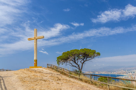 La Cruz de Benidorm La Creu giant cross on mountain hill Serra Gelada natural park, aerial view of Mediterranean Sea water with Costa Blanca coast and Benidorm city coastline in summer day, Spainの写真素材