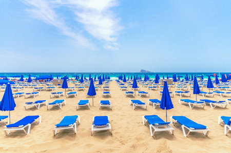 Levante sandy beach with chaise lounges and umbrellas, Playa Platja De Llevant in Benidorm city center on Costa Blanca coast Mediterranean Sea, Isla de Benidorm Island on horizon in summer day, Spainの写真素材
