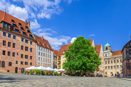 Sebalder Platz with medieval buildings, street restaurant outdoor cafe with tables and chairs in empty square in summer day in Old town Nuremberg city historical center, Bavaria state, Germanyの写真素材