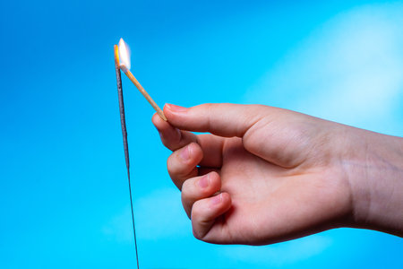 A child's hand holding a lit match.の写真素材