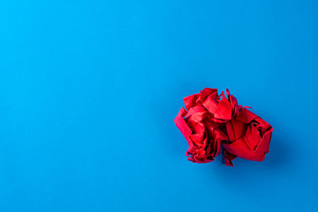 Red crumpled paper ball on blue