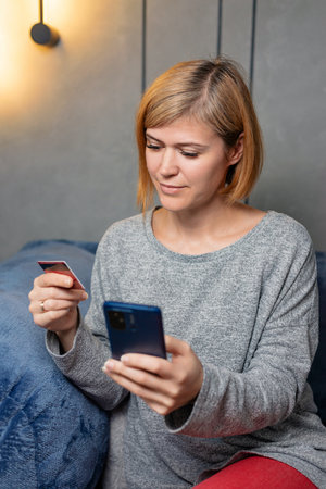 Young woman using smartphone while sitting casually on blue sofa