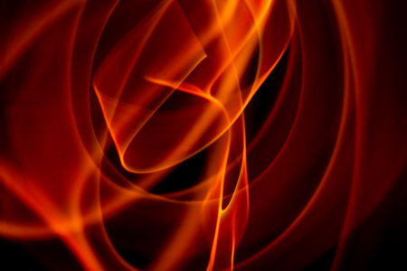 Smooth red flame curves forming elegant abstract fire motion with glowing highlights on black.の写真素材