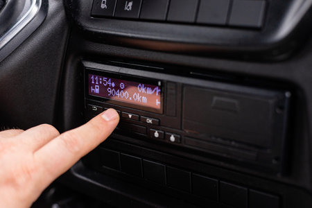 Close up of a male hand operating a professional digital tachograph system in a modern truck cabin...