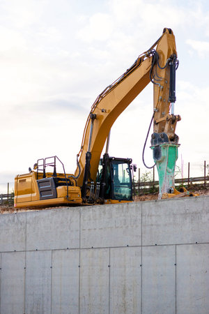 Industrial machinery performing earthworks and building foundation. Heavy equipment hydraulic arm at...
