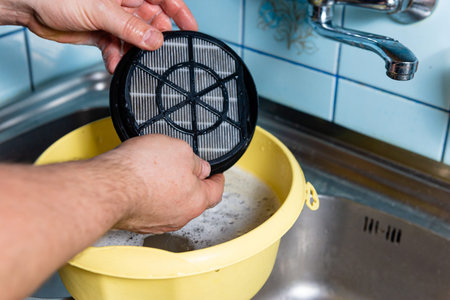 Demonstration of regular kitchen maintenance by cleaning the drain filter from dirt and food waste in a domestic environmentの写真素材