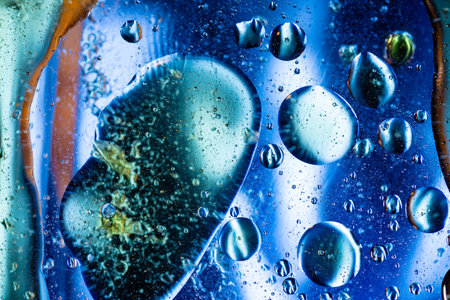 Mesmerizing blue abstract macro featuring oil and water interaction with transparent spheres,...