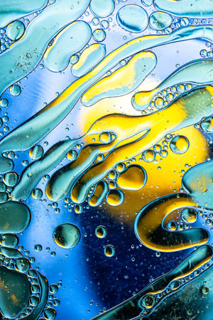 Vibrant abstract composition of colorful oil droplets and fluid lines, blending blue, yellow, and...